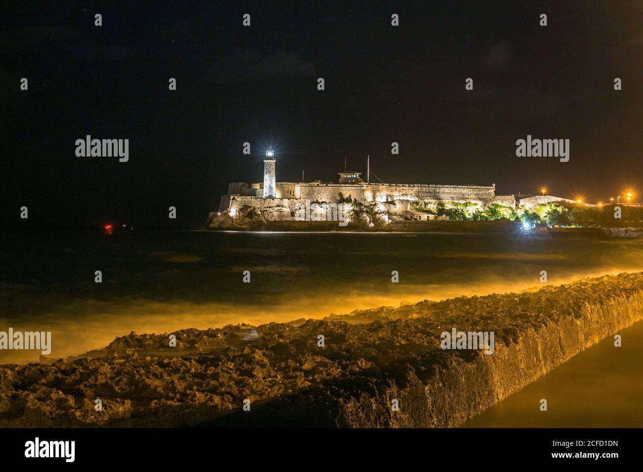 Blick von Malecon auf den Leuchtturm 'Faro del Castillo del Morro' bei Nacht in Havanna, Kuba Stockfoto