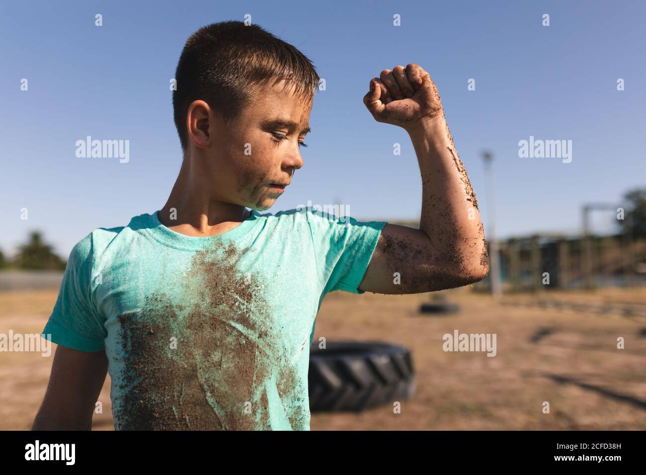 Junge, der seinen Bizeps bei einem Bootcamp beugend Stockfoto