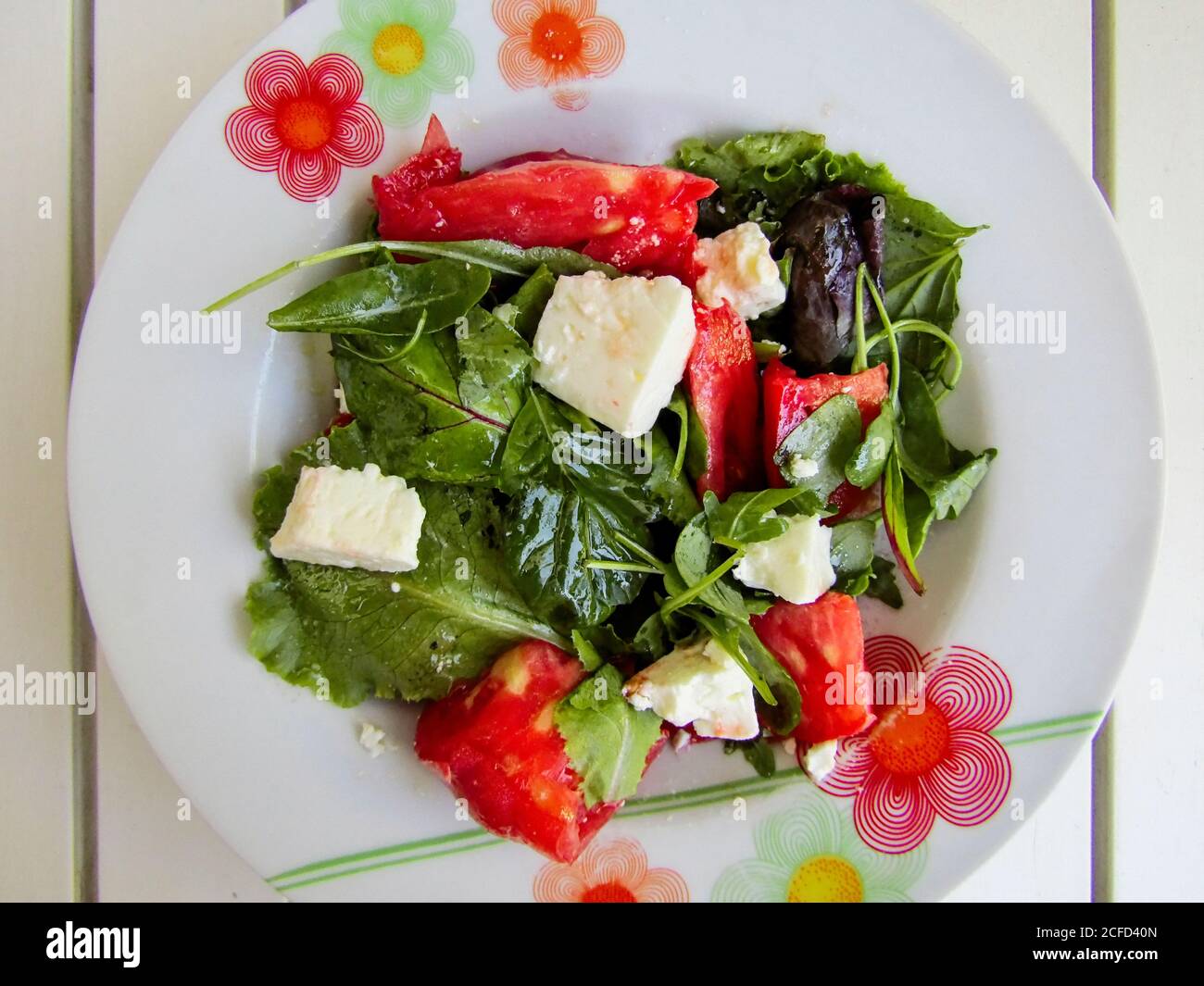 Roter und grüner Salat mit Feta-Käse, Tomate, Arugula plus Olivenöl und Balsamico-Essig Stockfoto