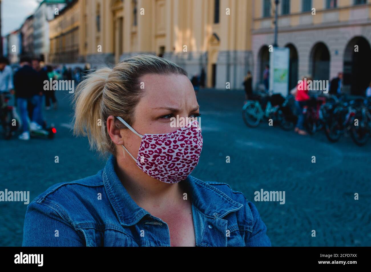 Blonde Frau mit Maske in Corona Times auf vollem Odeonsplatz In München Stockfoto