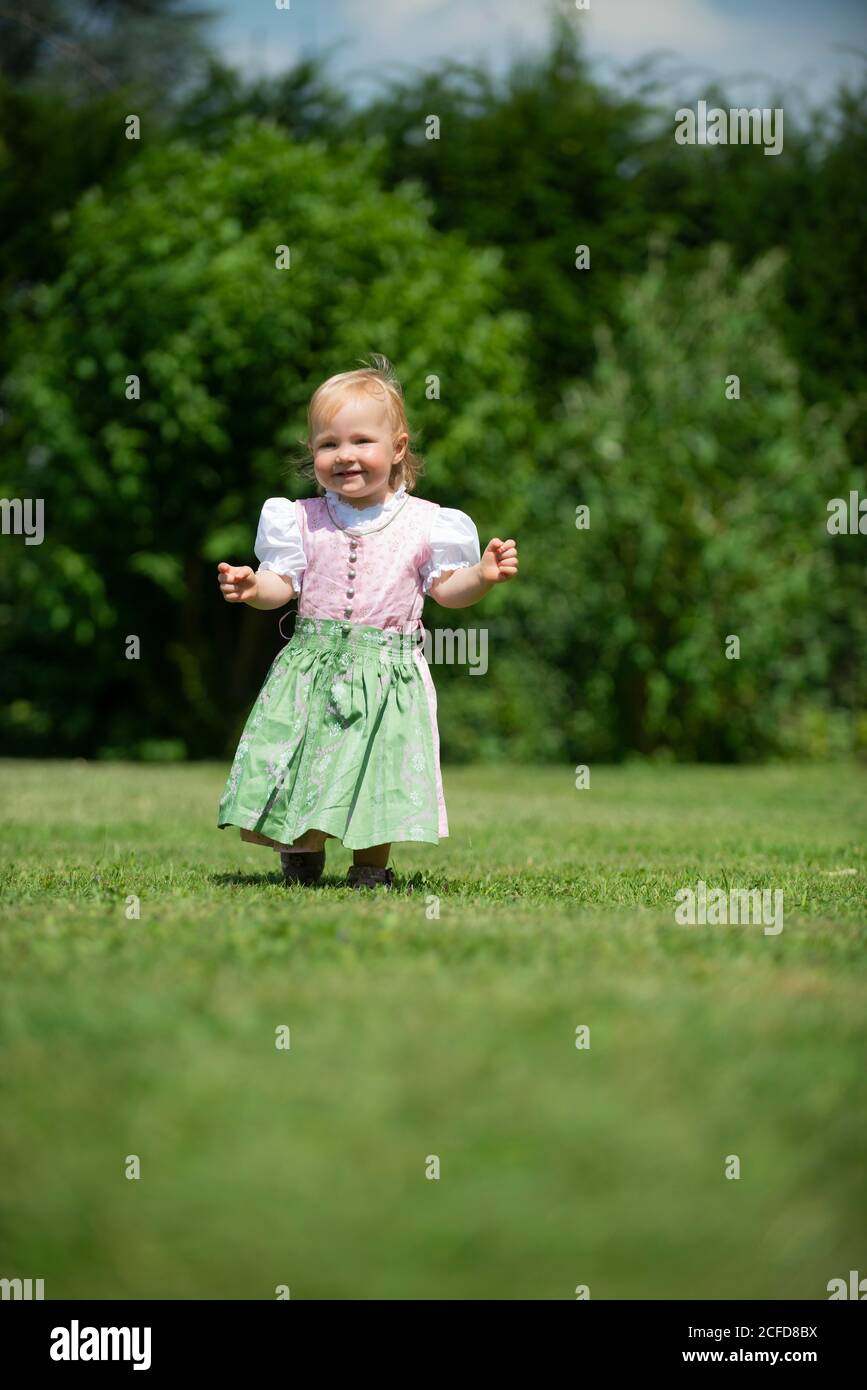 Mädchen in Dirndl läuft über eine Wiese, Oberbayern, Bayern, Deutschland Stockfoto