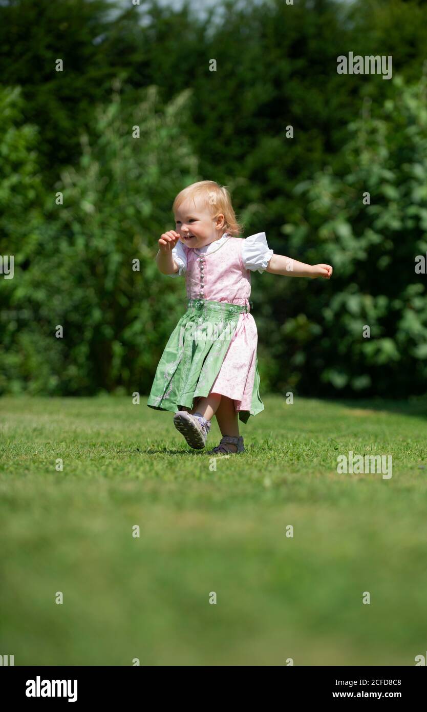 Mädchen in Dirndl läuft über eine Wiese, Oberbayern, Bayern, Deutschland Stockfoto