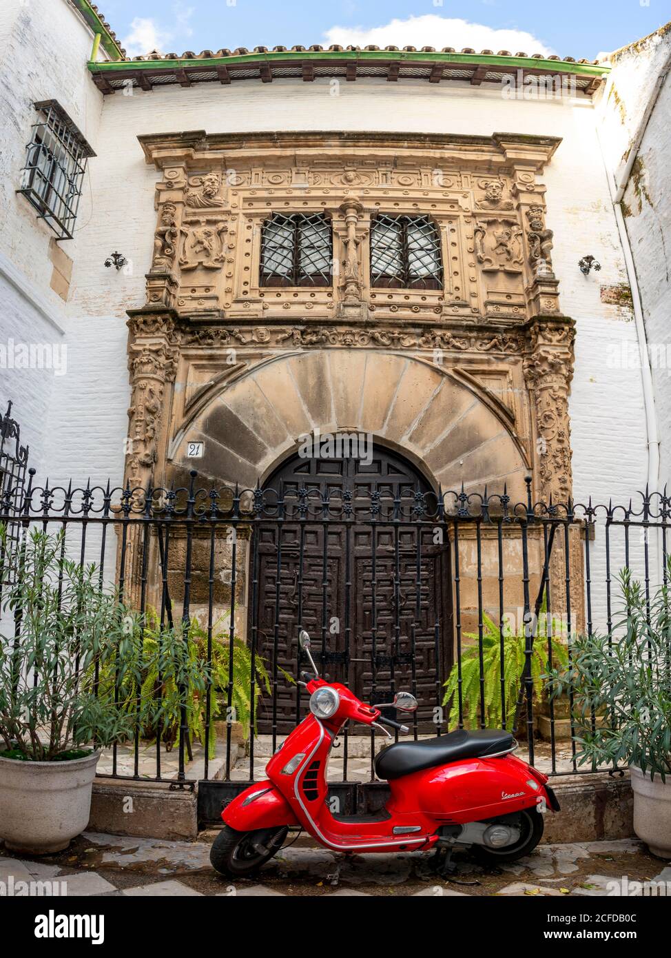 Roter Roller Piaggio Vespa vor einer Eingangstür, Santa Cruz, Sevilla, Andalusien, Spanien Stockfoto