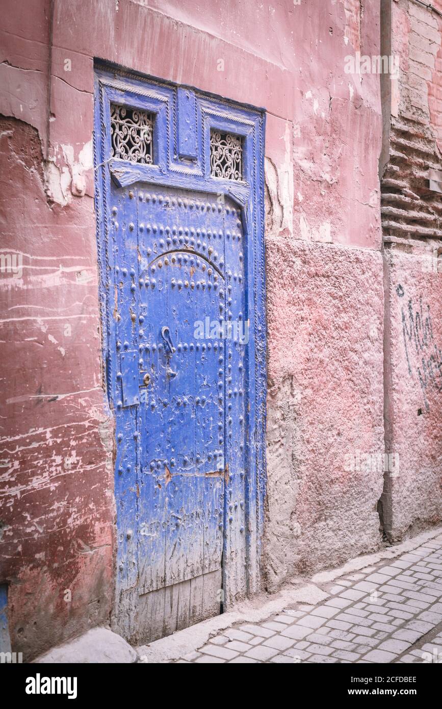 Veraltertes Gebäude mit schäbiger blauer Tür an der Straße von Marrakesch, Marokko Stockfoto