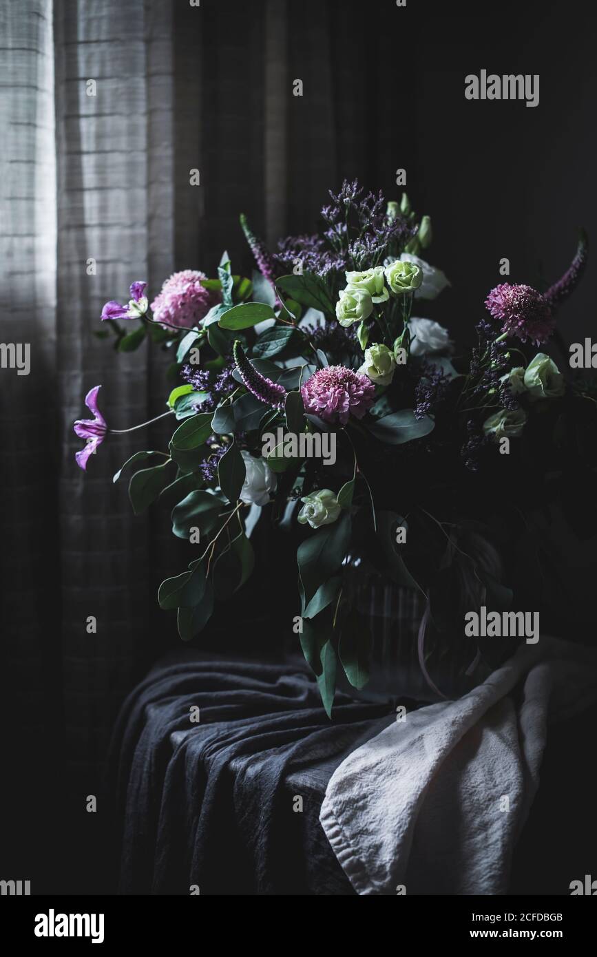 Erstaunlicher Blumenstrauß auf einem Tisch in einem dunklen Vintage-Zimmer Stockfoto
