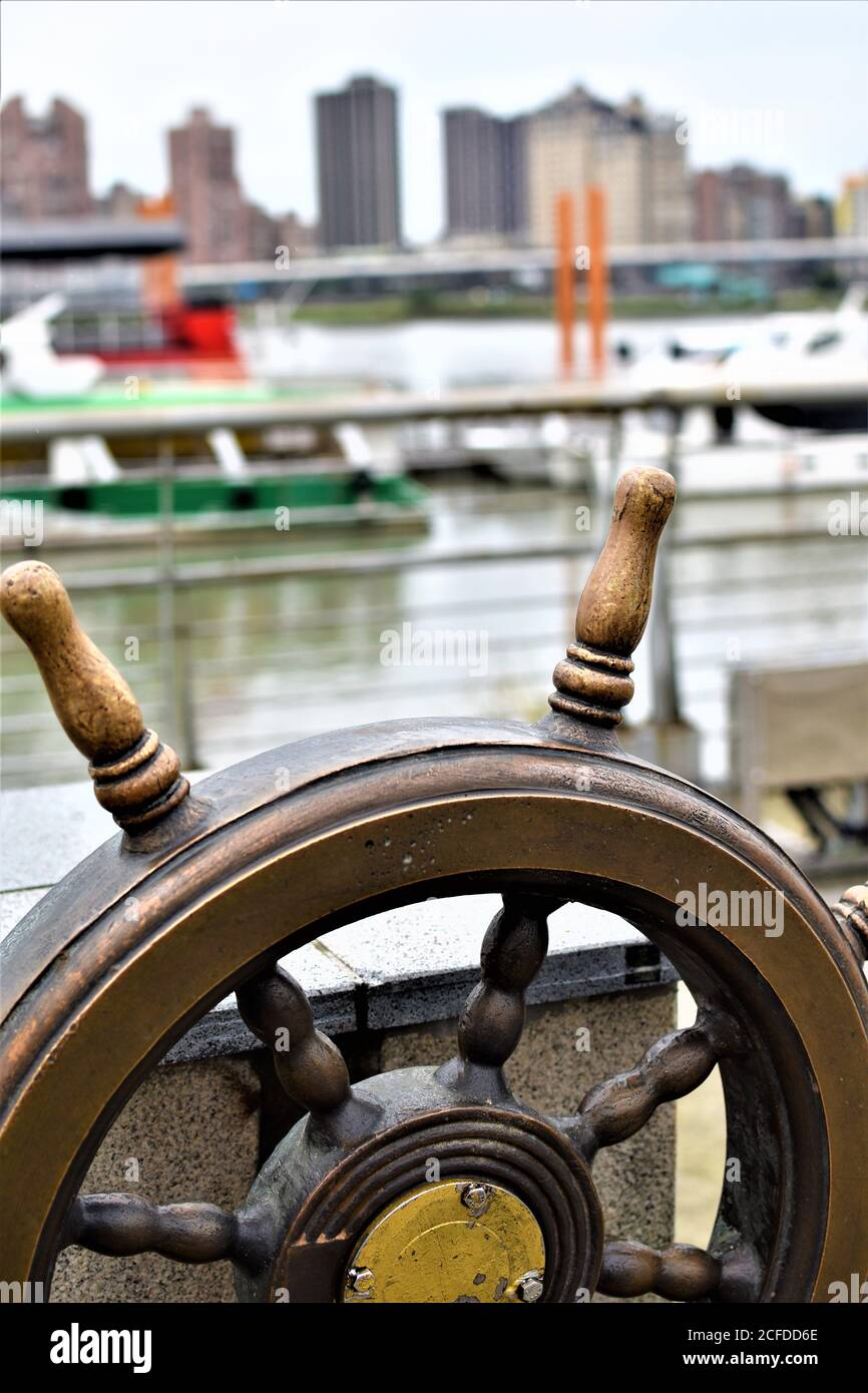 Ein bronzefarbenes Metalllenkrad an einem Park am Flussufer Stockfoto