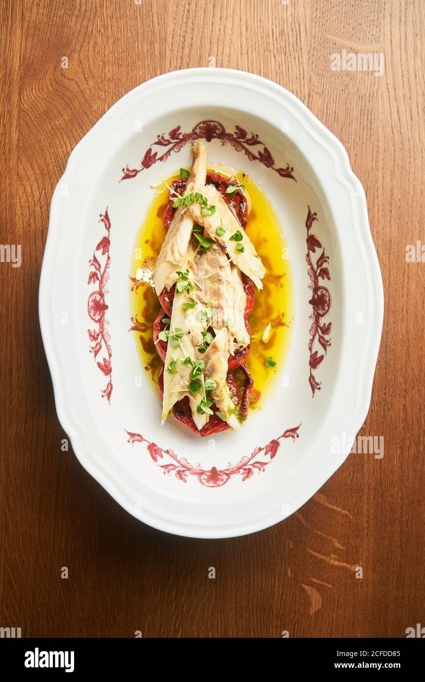 Von oben köstliche Thunfischstücke mit Tomatenscheiben auf dem Teller Auf dem Tisch Stockfoto