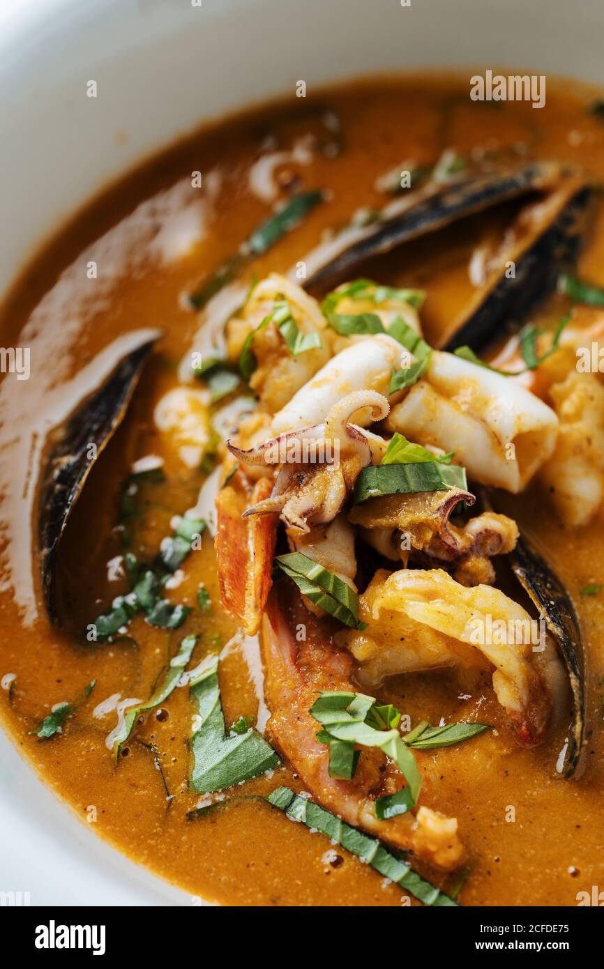 Von oben Nahaufnahme Ragout mit Fischmuscheln gekocht kleinen Tintenfisch Und Kräuter auf dem Teller im Restaurant Stockfoto