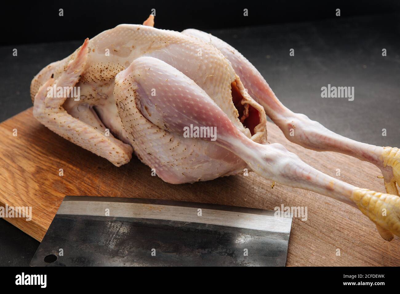 Cleaver und rohes Huhn auf Schneidebrett Stockfoto