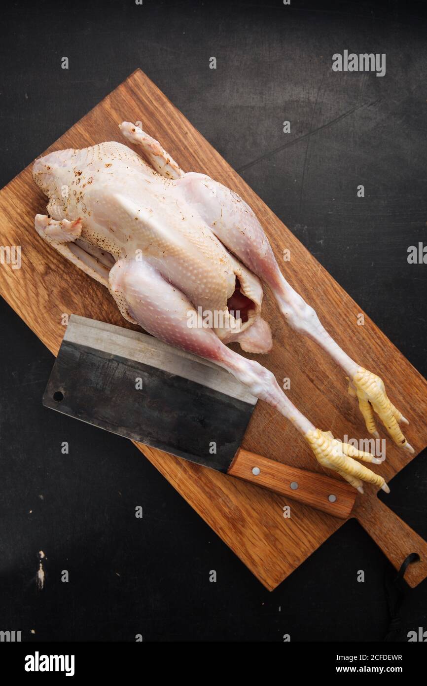Cleaver und rohes Huhn auf Schneidebrett Stockfoto