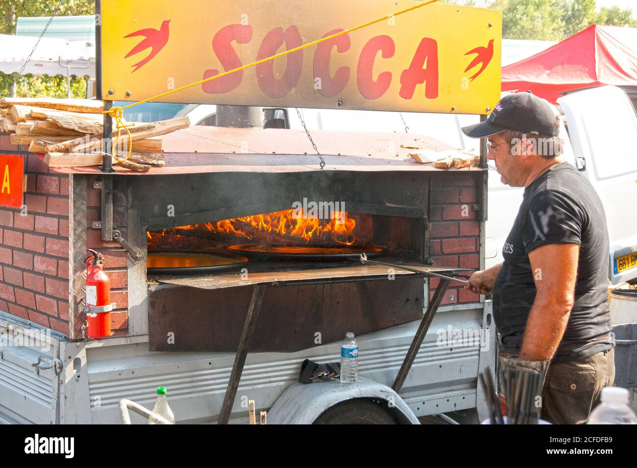 Flammen im Socca Ofen. Der Wochenend-Markt Pfannkuchen sind beliebt bei Käufern. Stockfoto