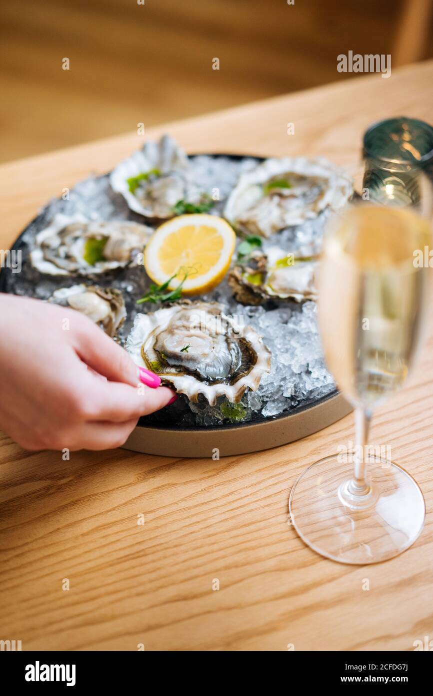 Unerkennbare Person mit einem Glas Champagner und leckeren Austern Mit ... Unerkennbare Person mit einem Glas Champagner und leckeren Austern Mit ...