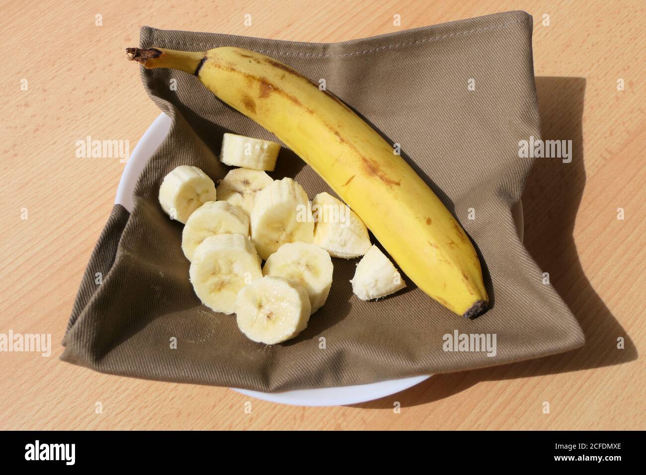 Banane in Scheiben serviert, fertig zum Essen mit Serviette Stockfoto