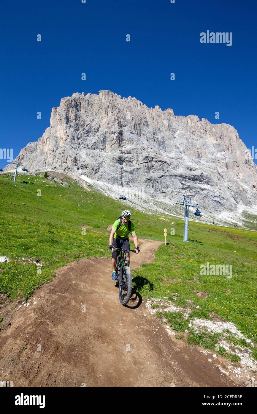 Radler mit Elektro-Mountainbike (E-Bike) bergab am Fuße des Langkofels, Gröden, Südtirol, Dolomiten, Italien Stockfoto