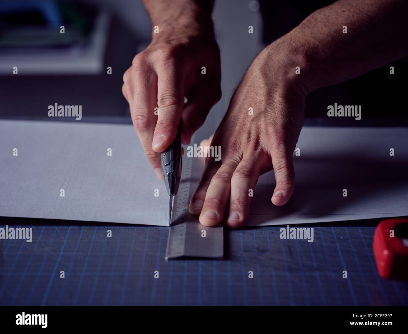 Arbeiter schneiden Blatt mit Schreibwarenmesser auf der Oberfläche Stockfoto