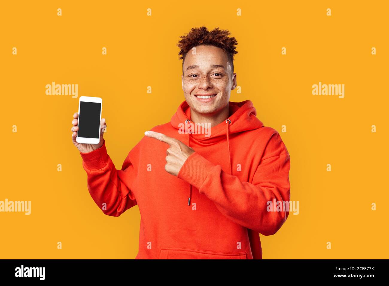 Junge Erwachsene männlich zeigt mit Finger auf dem Smartphone Stockfoto