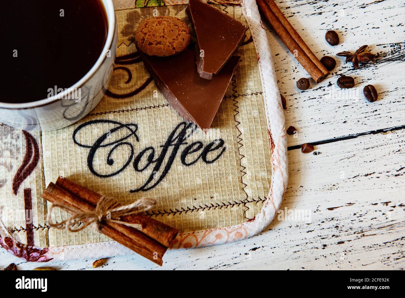 Kaffeebecher, Schokolade, Kaffeebohnen und Gewürze auf weißem Holztisch. Guten Morgen Frühstück oder Kaffeepause Set Hintergrund. Stockfoto