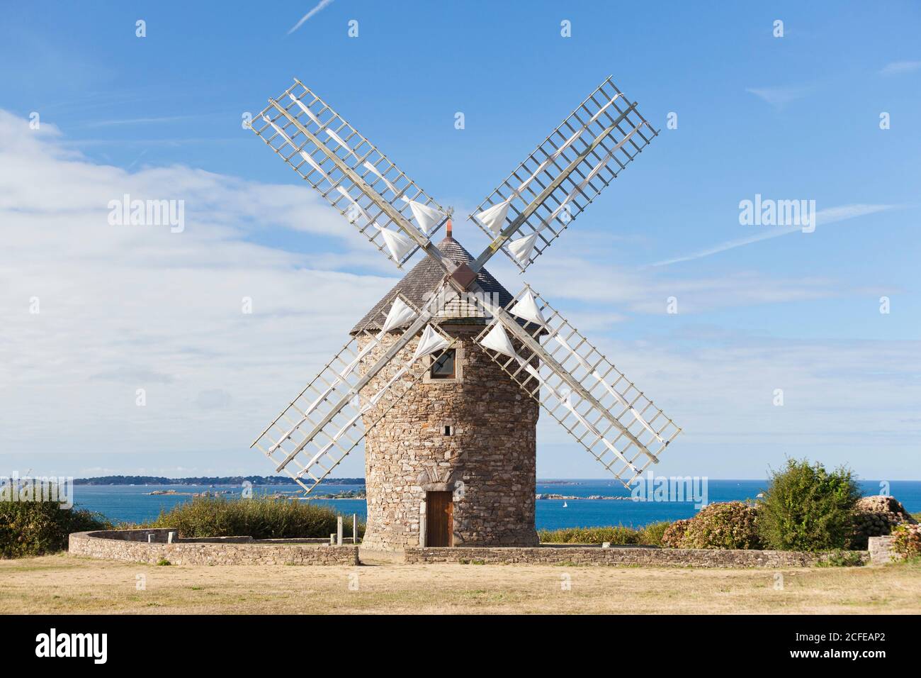 Eine traditionelle Windmühle an der bretonischen Küste unweit der Hafenstadt Paimpol. Von dort aus kann man die Insel Brehat sehen. Stockfoto
