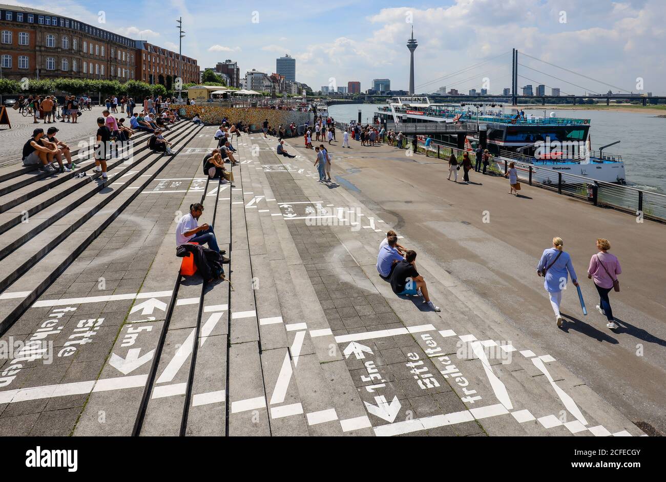 Düsseldorf, Nordrhein-Westfalen, Deutschland - Rheinpromenade in Zeiten der Coronapandemie sitzen Menschen auf der Rheintreppe am Burgplatz daneben Stockfoto