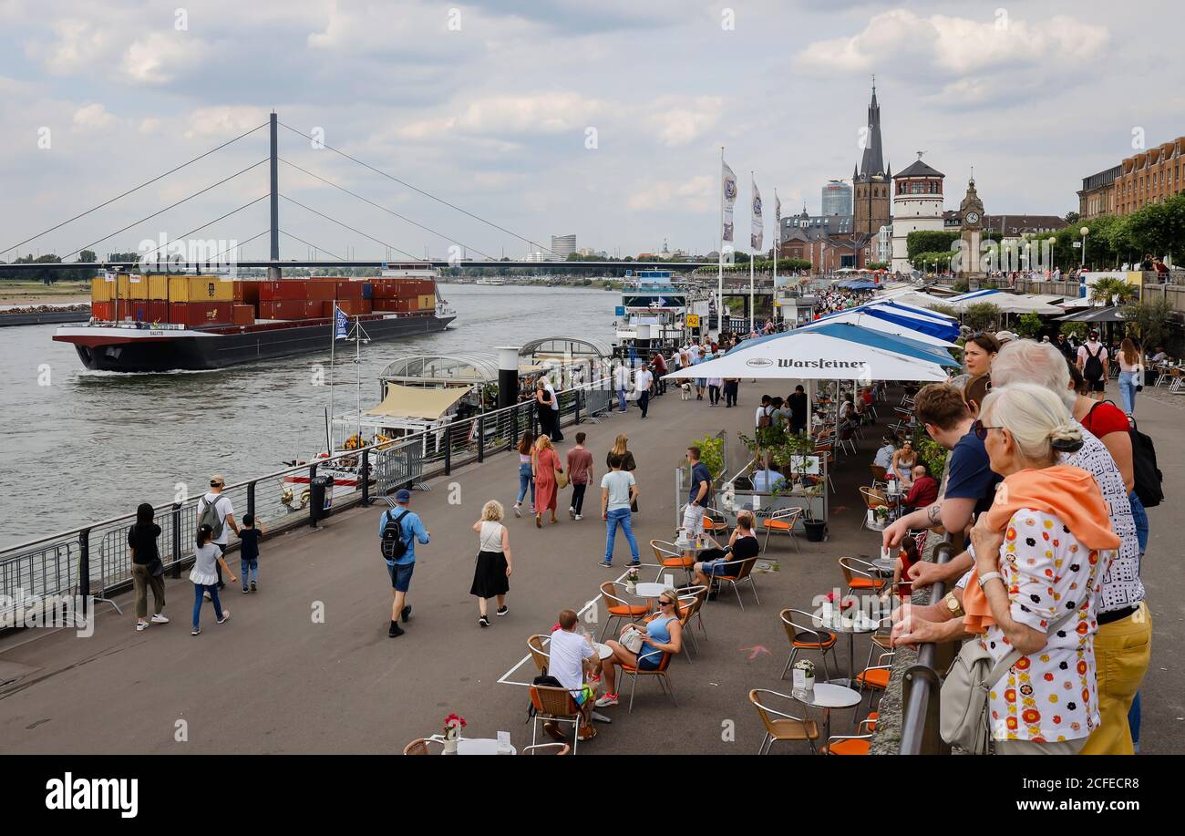 Düsseldorf, Nordrhein-Westfalen, Deutschland - Rheinpromenade in Zeiten der Coronapandemie laufen die Menschen am Rheinufer und sitzen im Stockfoto