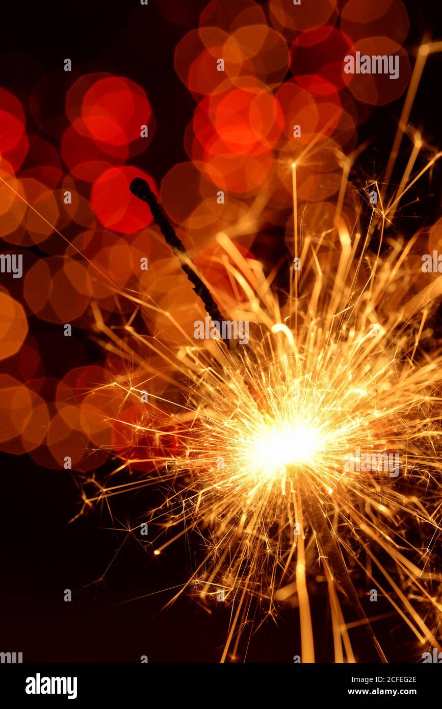 Brennender Funkler gegen goldenes Bokeh auf schwarzem Hintergrund Stockfoto