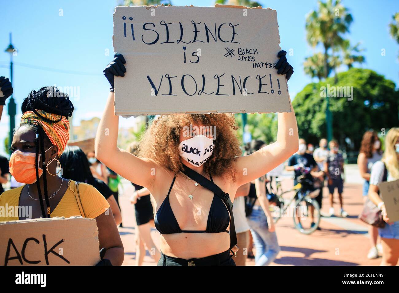Ethnische Frauen protestieren gegen Rassismus in der Stadt mit Schweigen ist Gewalt und schwarze Leben Materie Karton Poster an sonnigen Tag In einer überfüllten Straße Stockfoto