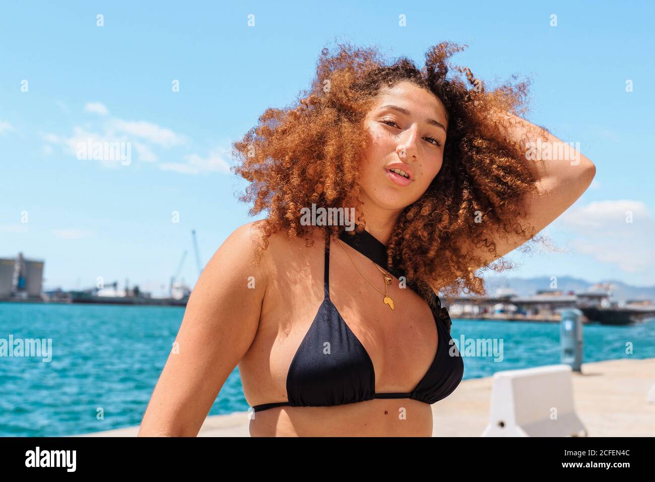Von unten Inhalt weiblich in Bikini-Top genießen Sommer An sonnigen Tagen und Blick auf die Kamera Stockfoto