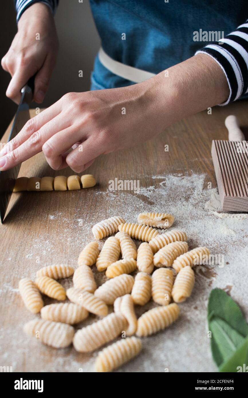 Anonymer weiblicher Schneid-Teig für hausgemachte Gnocchetti Pasta auf dem Tisch In der Küche Stockfoto