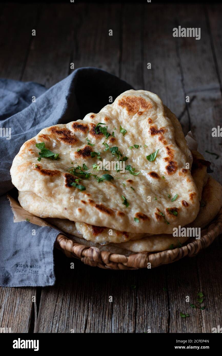 Teller mit leckerem Naan Brot und Stoffserviette Verwitterter Holztisch Stockfoto