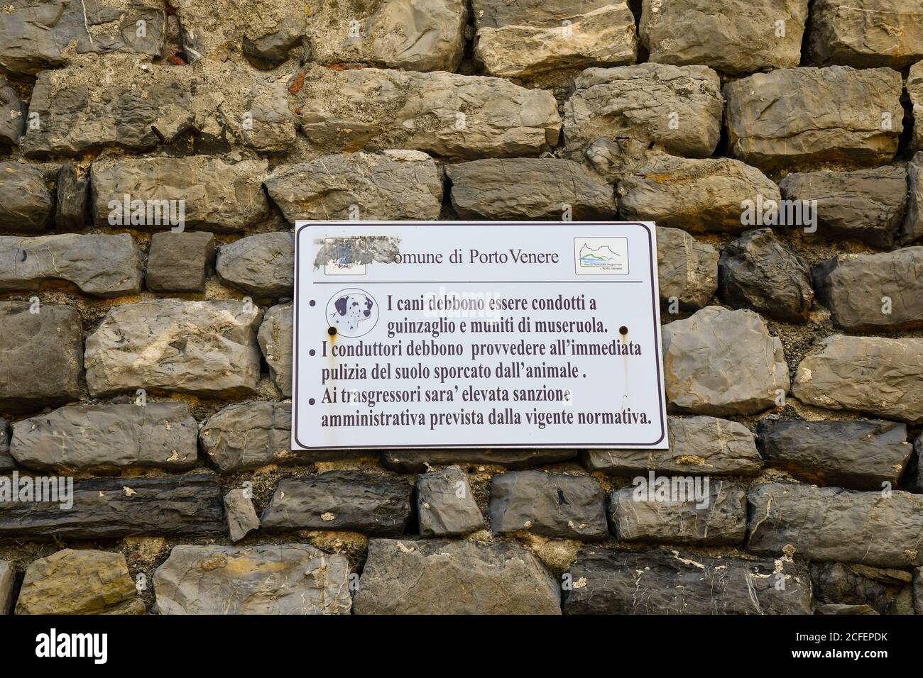 Zeichen auf einer Steinmauer mit den kommunalen Gesetzen für die Hundebesitzer: Verwenden Sie Leine und Schnauze und abholen nach Hund, Porto Venere, La Spezia, Ligurien, Italien Stockfoto