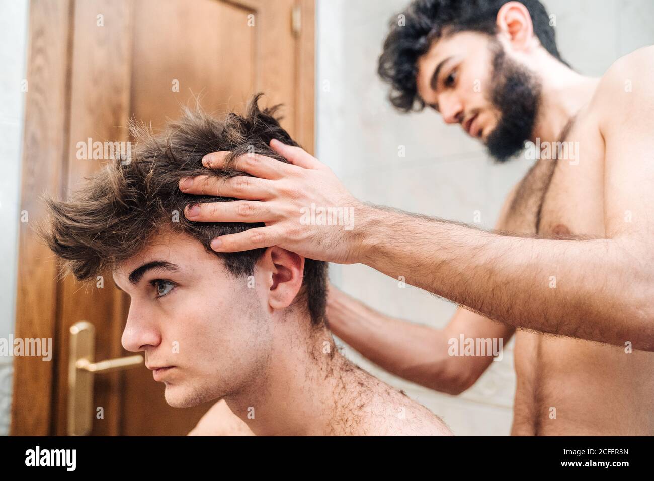 Männlich mit Haarschneider Schneiden Haare von Kerl in zeitgenössischen Badezimmer zu Hause Stockfoto