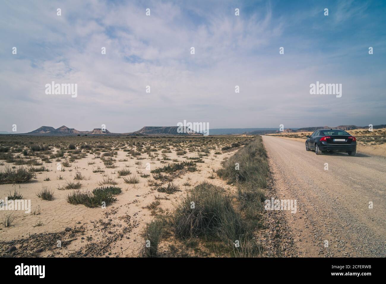 Rückansicht des schwarzen Autos, das auf leerer Straße entlang fährt Halbwüste mit trockener Vegetation in Bardenas Reales Navarra Spanien Stockfoto