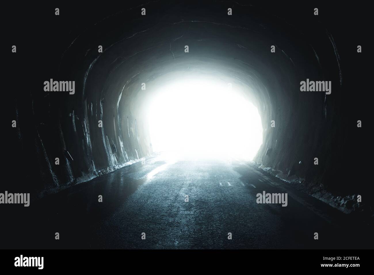 Helles Licht scheint am Ende des grungigen Tunnels mit Asphalt Straße Stockfoto