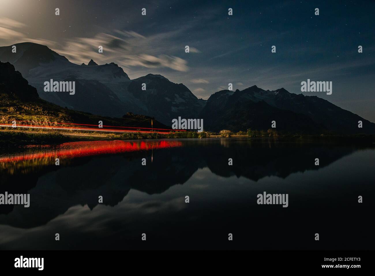Dramatische atemberaubende Landschaft von rot beleuchteten Ufer und dunklen ruhigen Wasser Reflektierender wolkig Himmel und Berge am Abend in der Schweiz Stockfoto