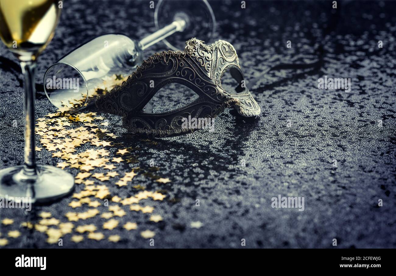 Karnevalsmaske und Glas mit sternförmigen Konfetti. Stockfoto