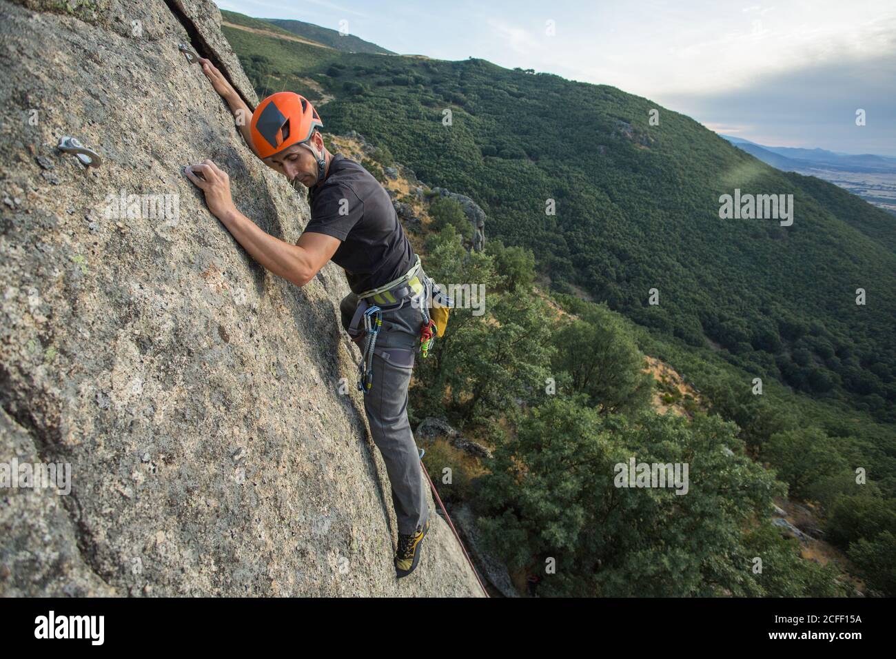 Mann klettert in der Natur mit Kletterausrüstung auf einen Felsen Stockfoto