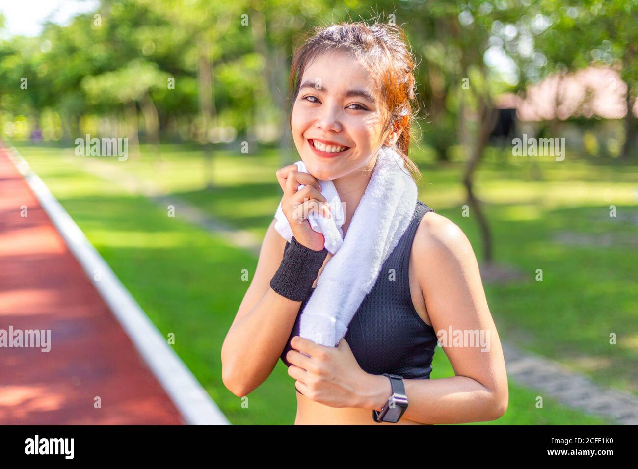 Happuy schöne junge asiatische Frau beim Training auf einer Laufstrecke Mit ihrem weißen Handtuch nach ihr schwitzt sie ab Morgenlauf Stockfoto