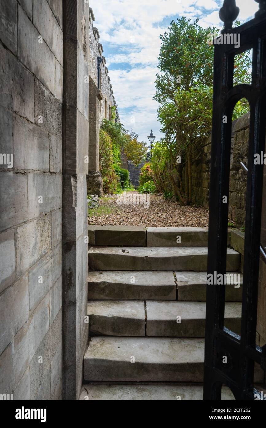 Ein Tor, das über eine Treppe zu einem schmalen Durchgang mit einem geheimen privaten Garten in Arundel, West Sussex, England, Großbritannien, offen gelassen wurde. Stockfoto