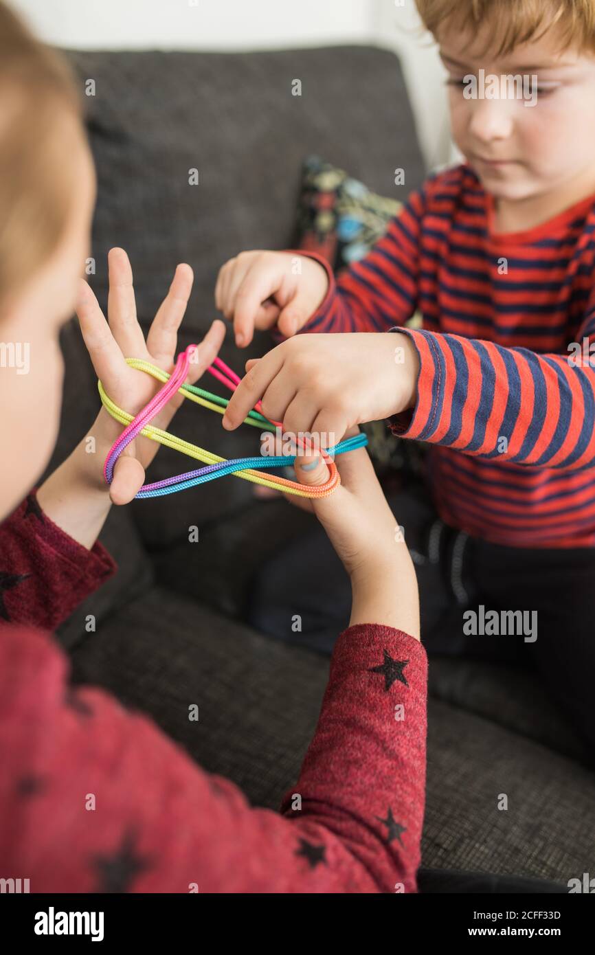 Von oben von kleinen Kindern spielen mit bunten Gummis auf Palmen zusammen zu Hause Stockfoto