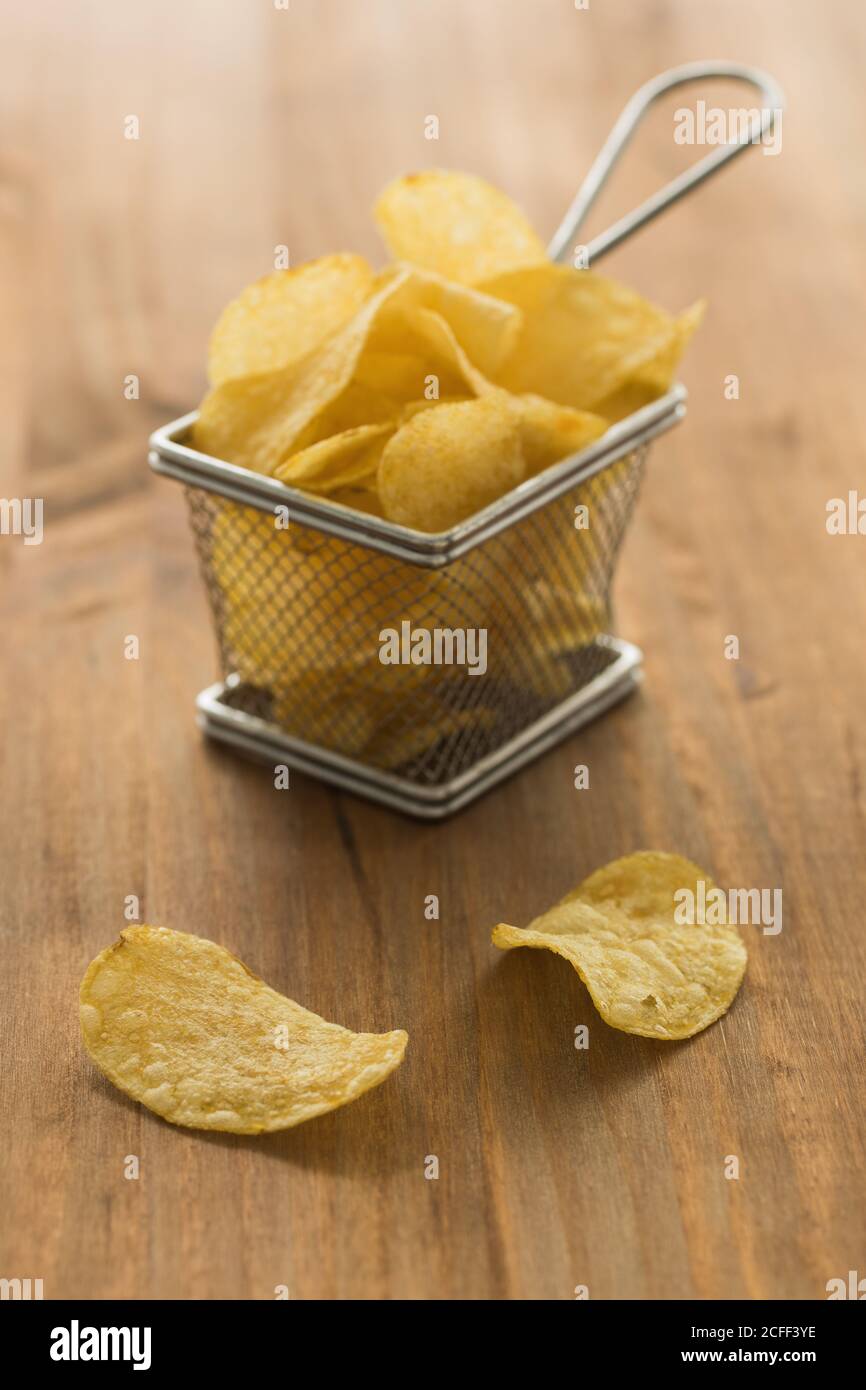Knusprige Kartoffelchips auf Holztisch in der Küche platziert Stockfoto