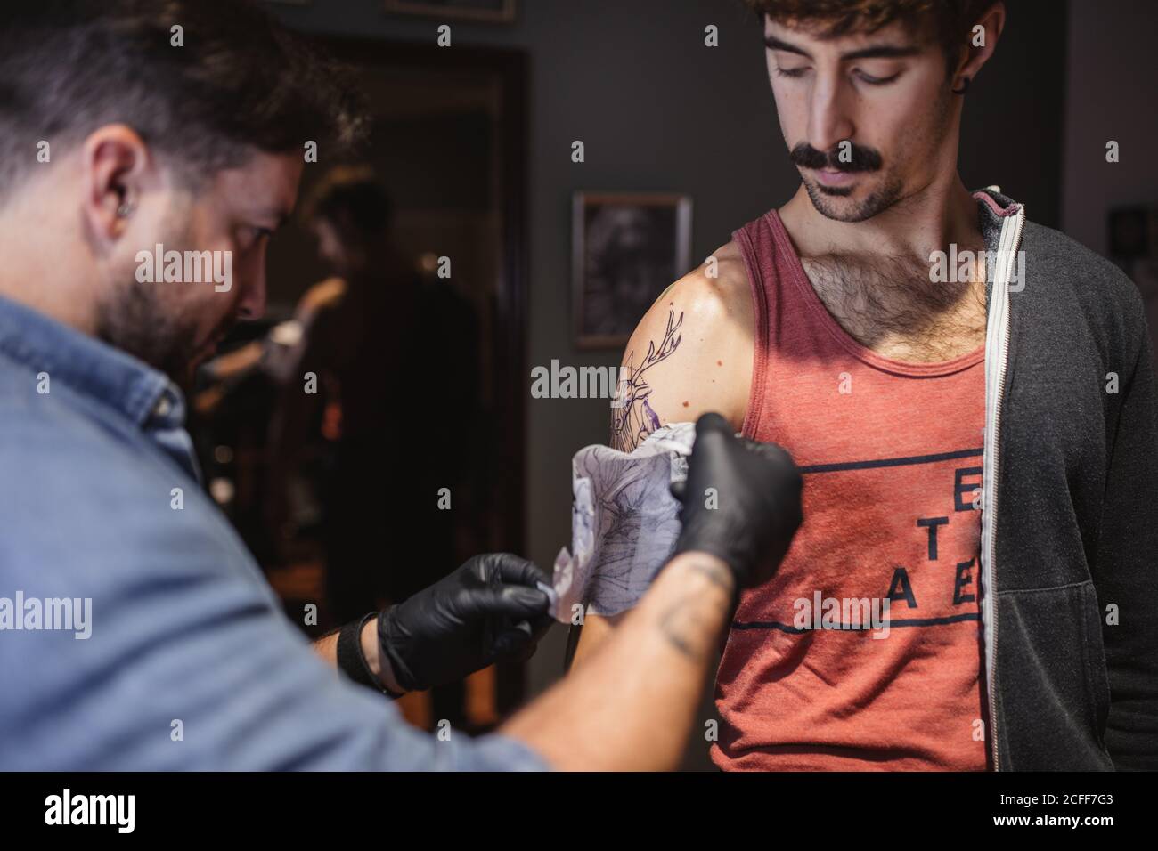 Tattoo-Master Vorlage auf dem Unterarm des Kunden entfernen Stockfoto