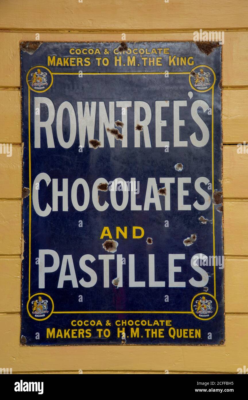 Hampshire, England, Großbritannien. 2020. Eine rostende Vintage-Metall-Werbung für Rowntrees Schokolade und Pastillen von einem berühmten Hersteller, an der Wand montiert. Stockfoto