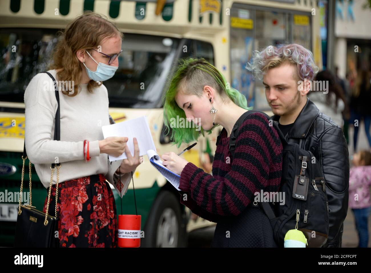 Junge Frau mit grünem Haar, die eine Petition unterschreibt Stockfoto