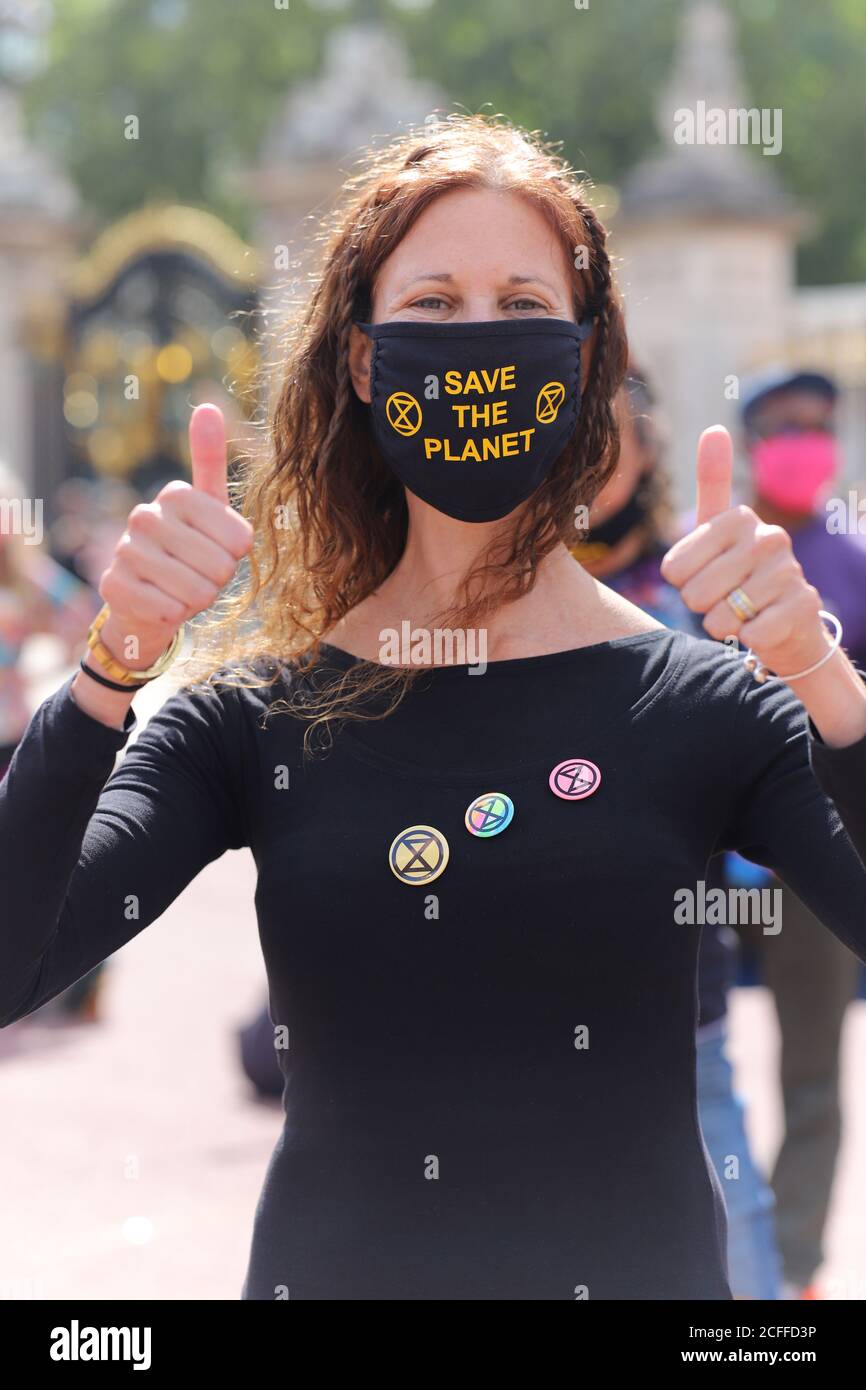 Extinction Rebellion-Aktivisten vor dem Buckingham Palace in London veranstalten einen Diskobedienz-Tanz, 5. September 2020. Eine weibliche Protesterin trägt eine Gesichtsmaske, die sagt, den Planeten zu retten und XR-Abzeichen Stockfoto