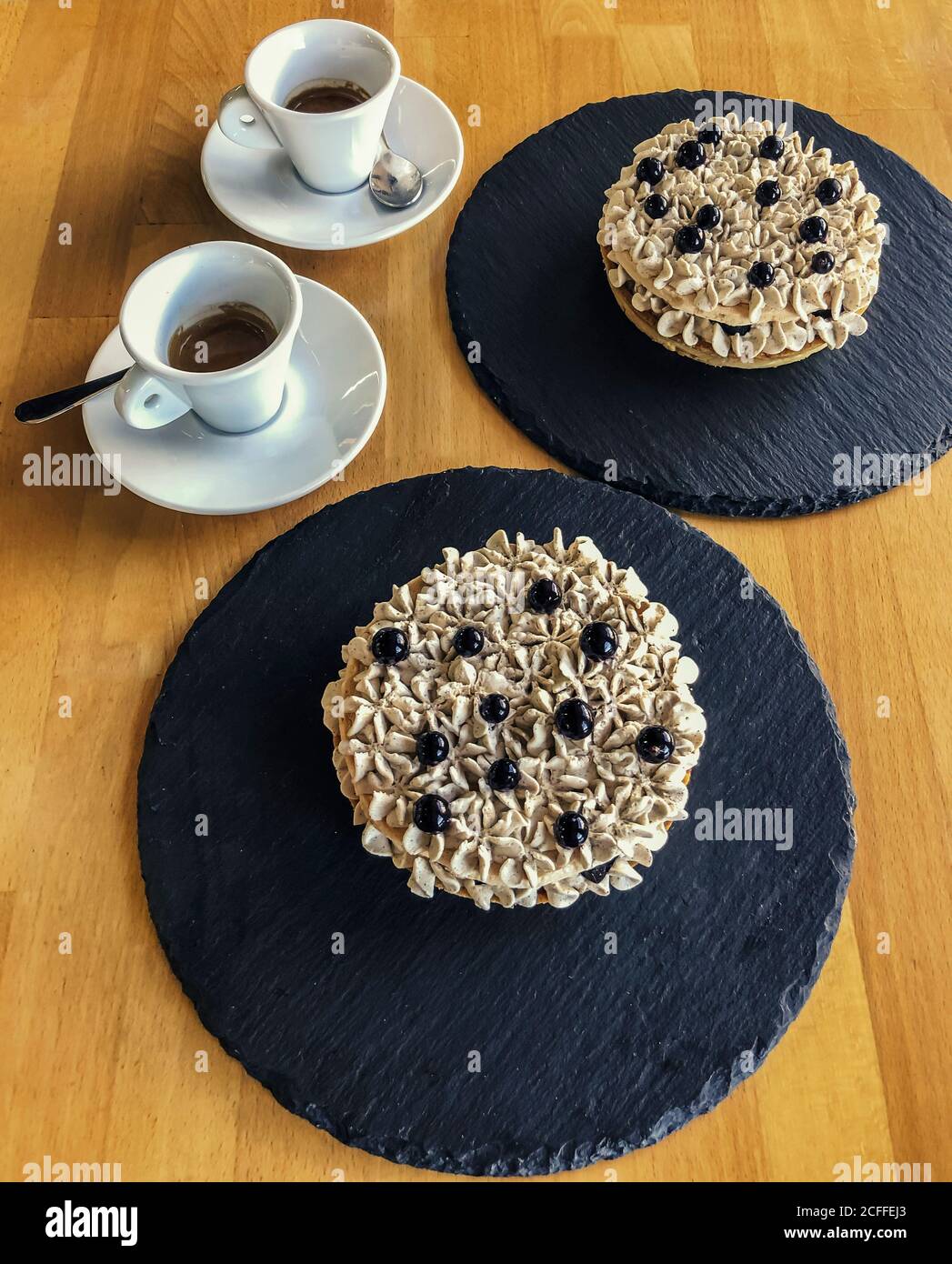 Zwei Shortbread Körbe mit Sahne und Heidelbeeren und ein Paar Von Tassen Kaffee Stockfoto