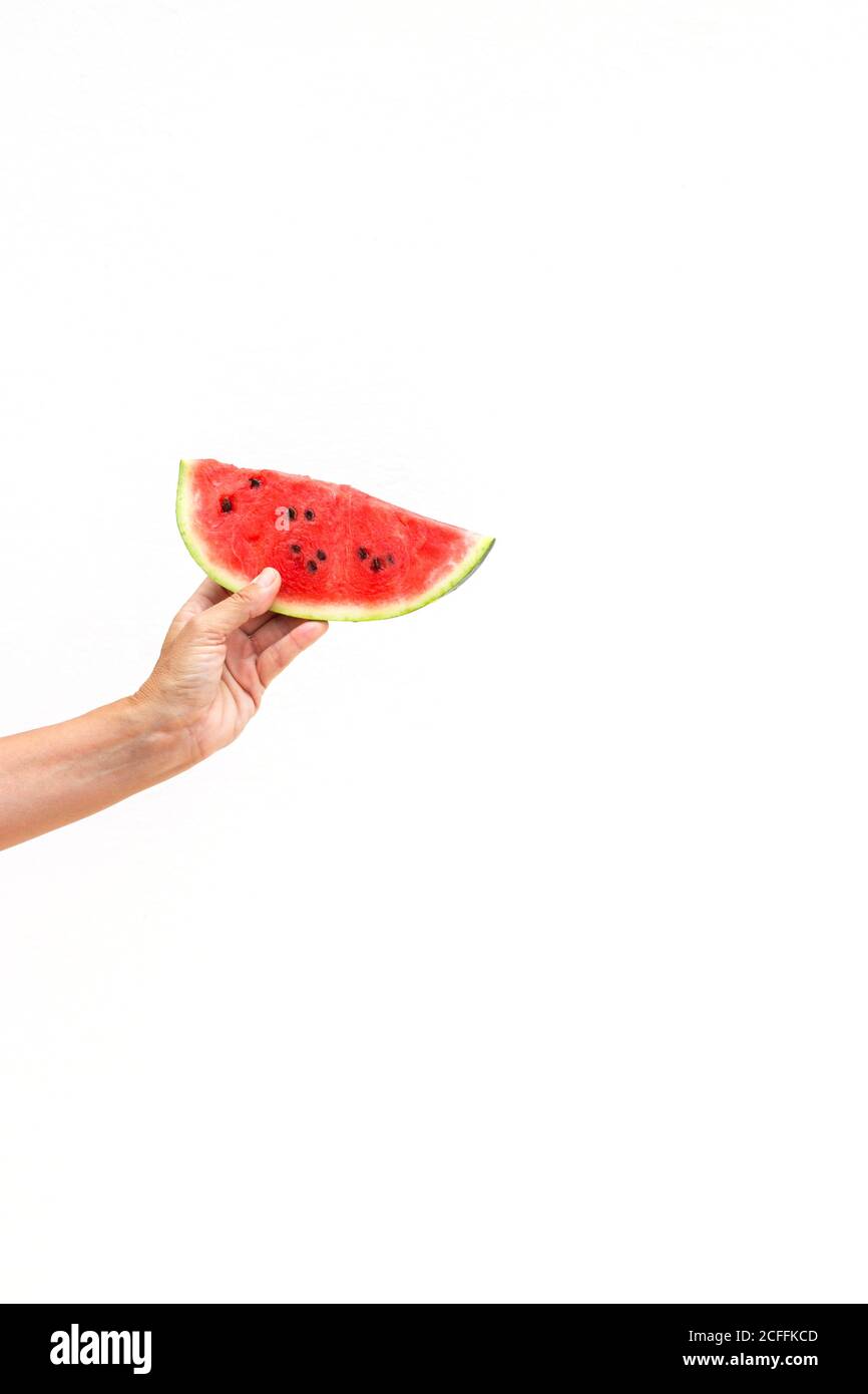 Hand der anonymen Person, die ein Stück saftige süße Wassermelone hält Vor weißem Hintergrund Stockfoto