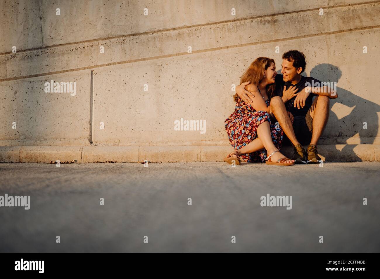 Mann und Frau schauten einander an und umarmten sich an der nahe gelegenen Straßenmauer Stockfoto