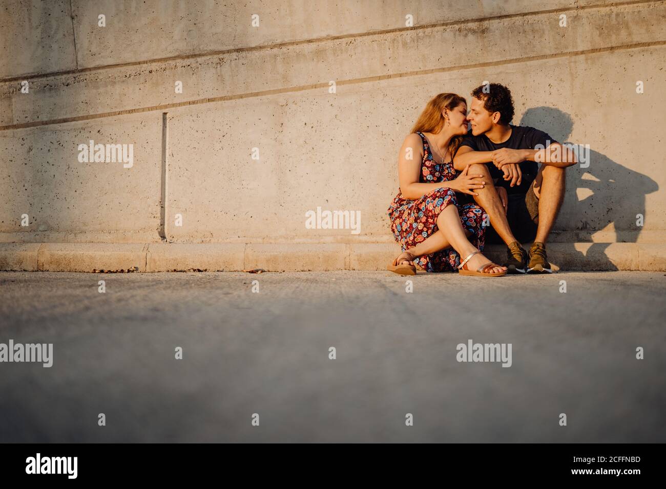 Mann und Frau schauten einander an und küssten sich an der nahe gelegenen Straßenmauer Stockfoto