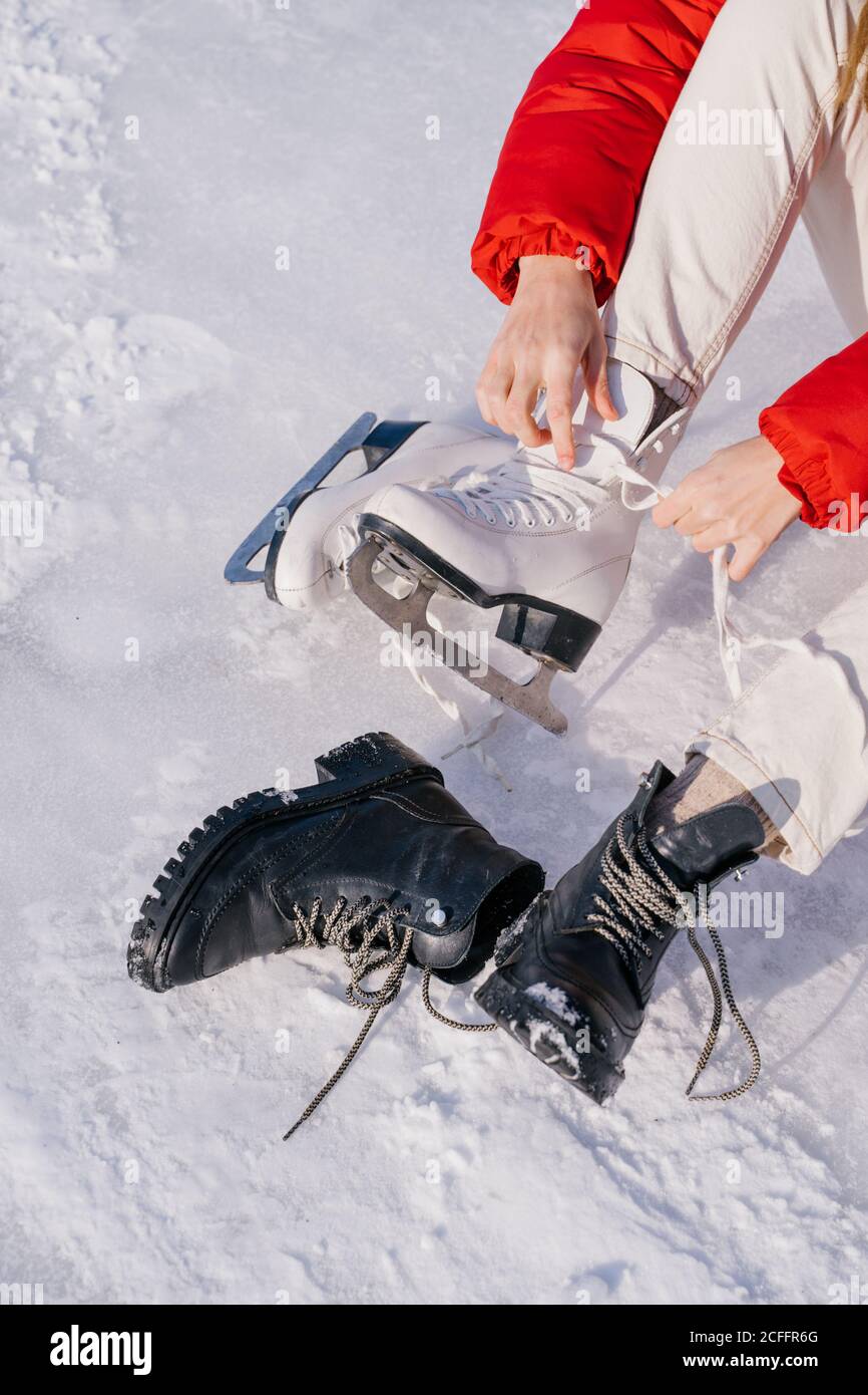 Frau auf Schnee sitzend und Stiefel wechselnd Stockfoto