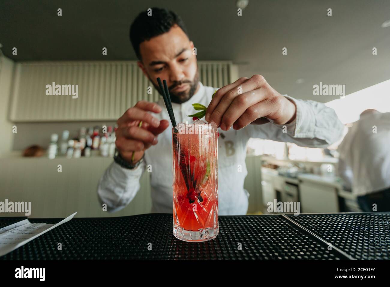 Fröhlicher Mann, der in einer Bar alkoholische Getränke zubereitete. Stockfoto